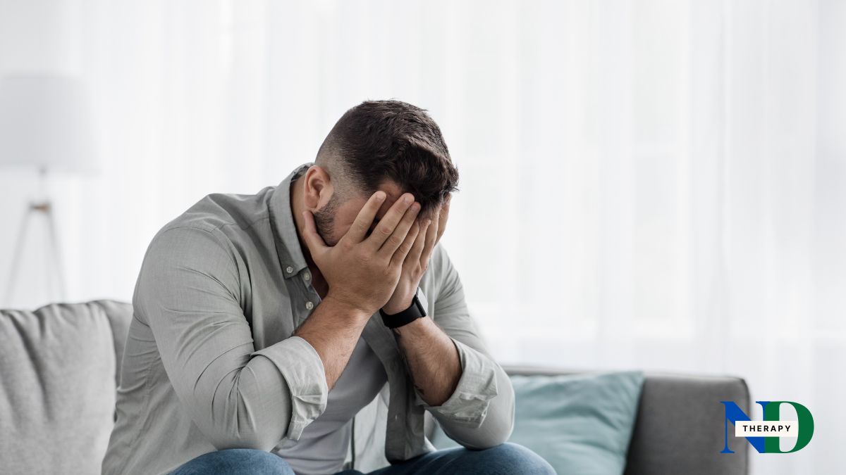 Man sitting with hands over his face expressing shame.