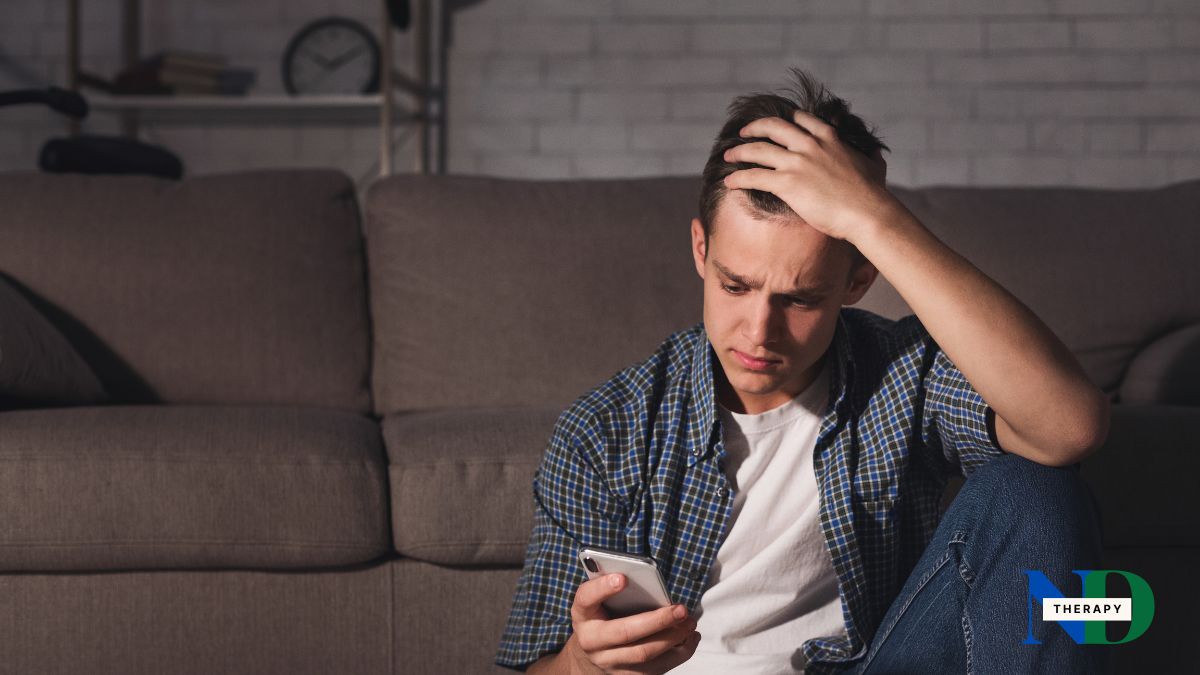 A male teen is looking at his phone.