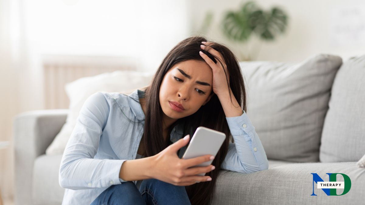 A young woman staring at her phone, stressed.