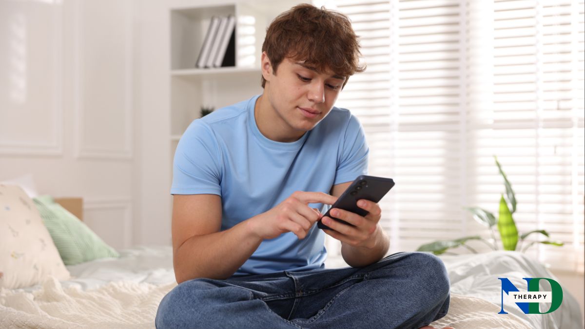 Teenager sitting on a bed, typing on their phone.